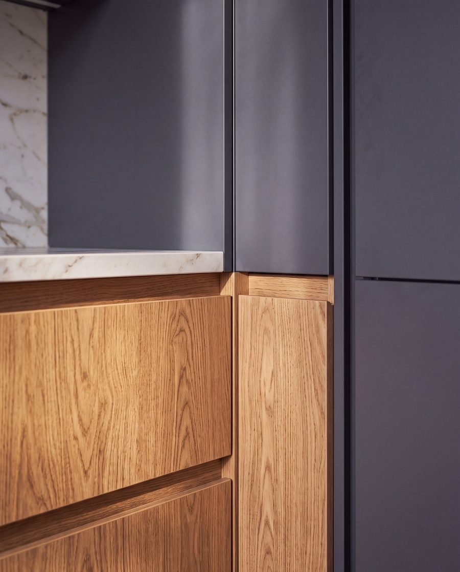 Handleless oak cabinetry meeting charcoal tall units